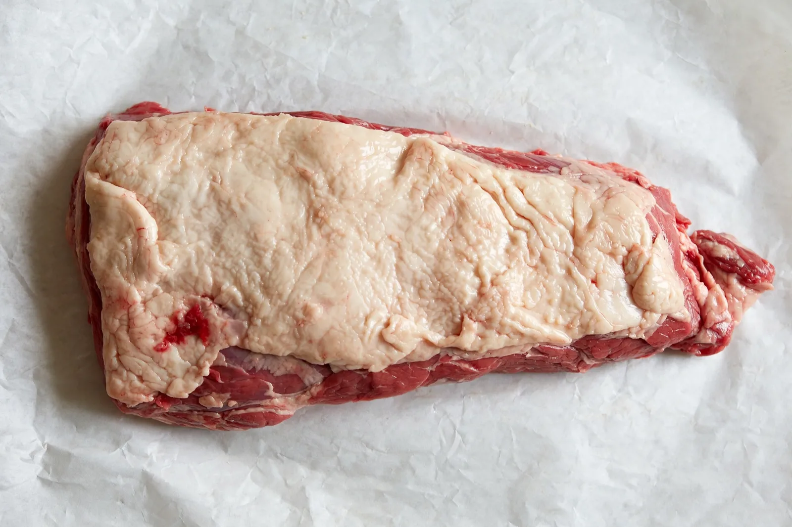Whole raw kosher beef brisket with fat cap on white butcher paper — Satmar Meats Brooklyn